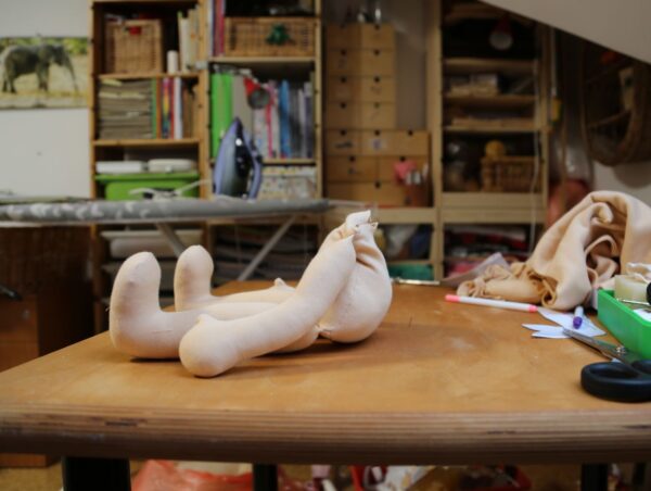 rozešitá látková panenka, waldorfská panenka z tělového úpletu. Torzo panenky sedí na stole. ekopanenky.cz Tereza Jarošová Jak začít šít panenku bez chaosu